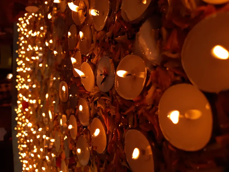 Glowing tea-light candles placed over orange flower petals during Diwali.
