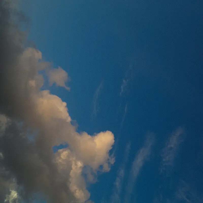 Grainy aesthetic cloud illuminated by golden hour light against a deep blue backdrop.